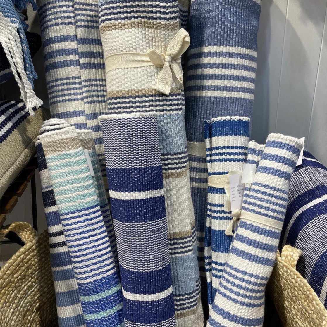 Rolled blue and white striped rugs standing upright in a retail display.