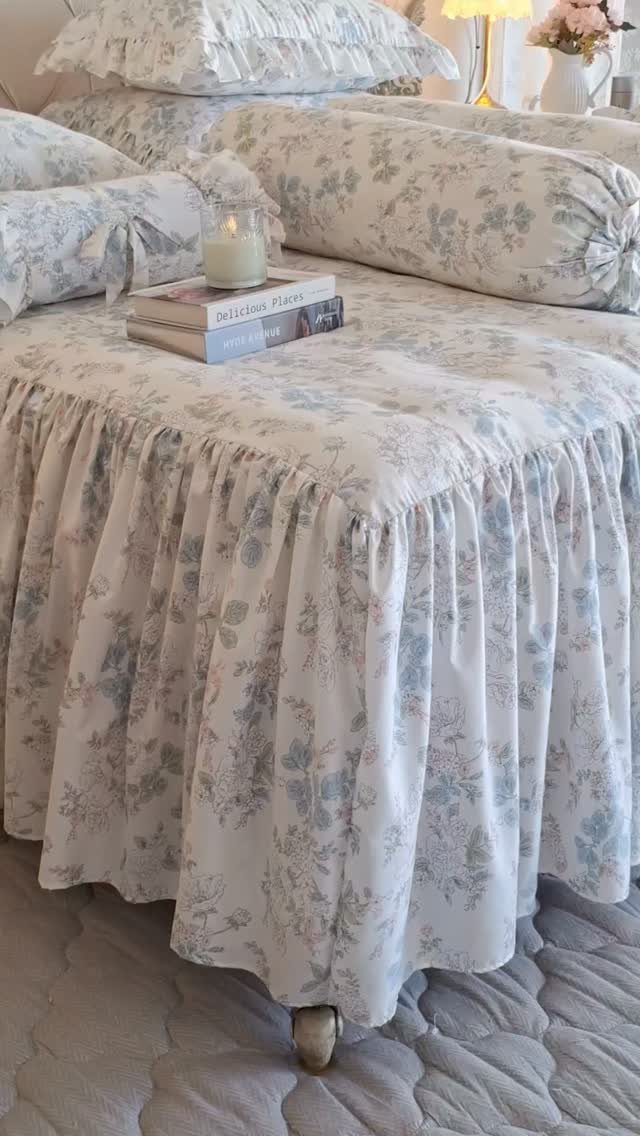 Lightweight floral bedding with blue patterns and ruffles on a bed with books.