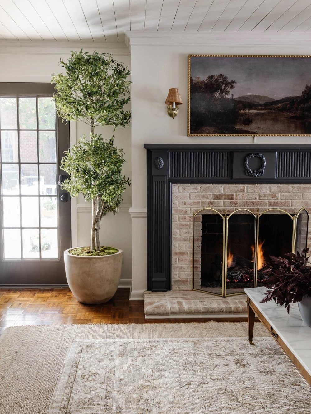 Layered neutral rugs on a hardwood floor in front of a black fireplace.