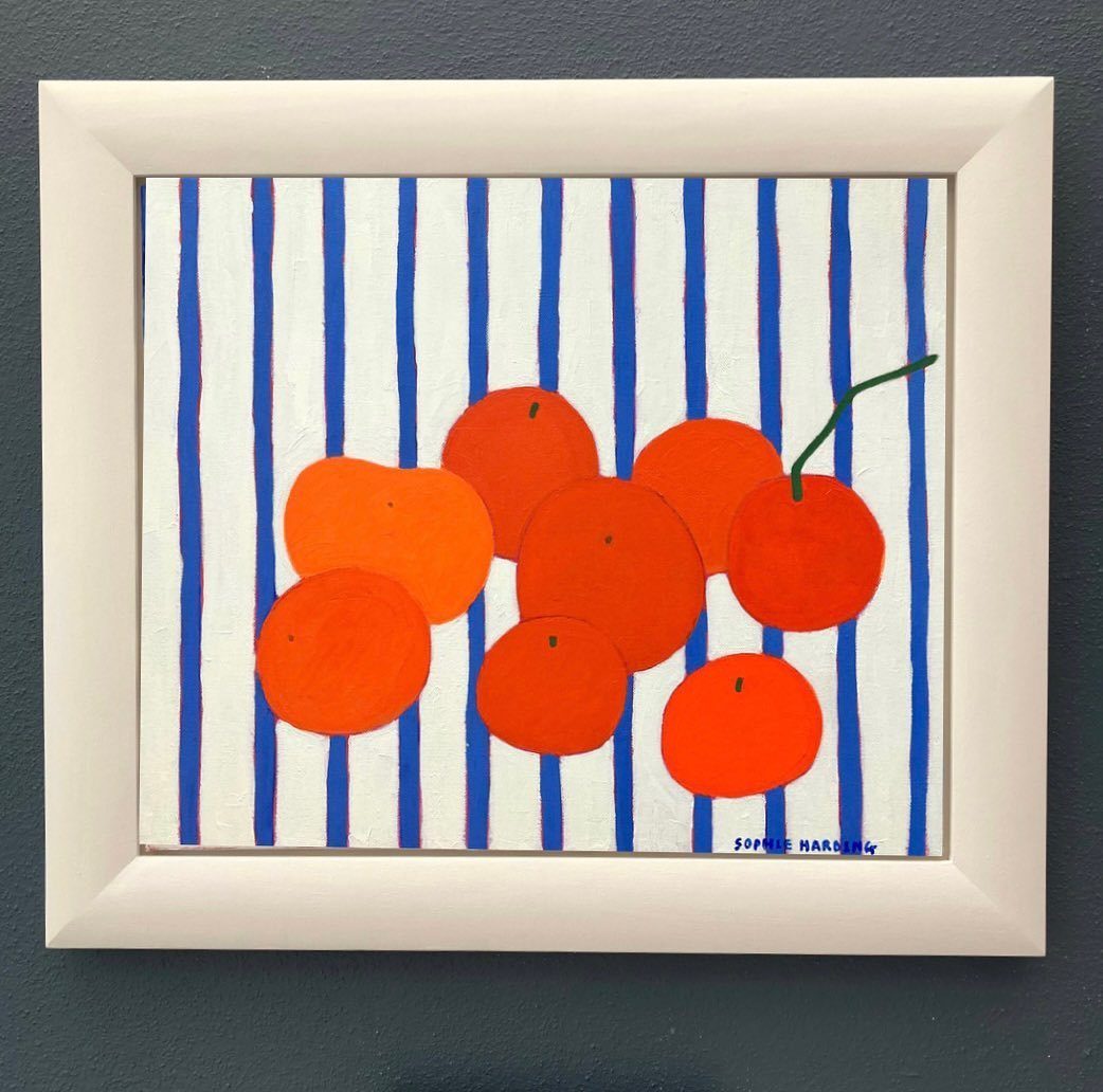 Framed painting of orange citrus fruits on a blue and white striped background.