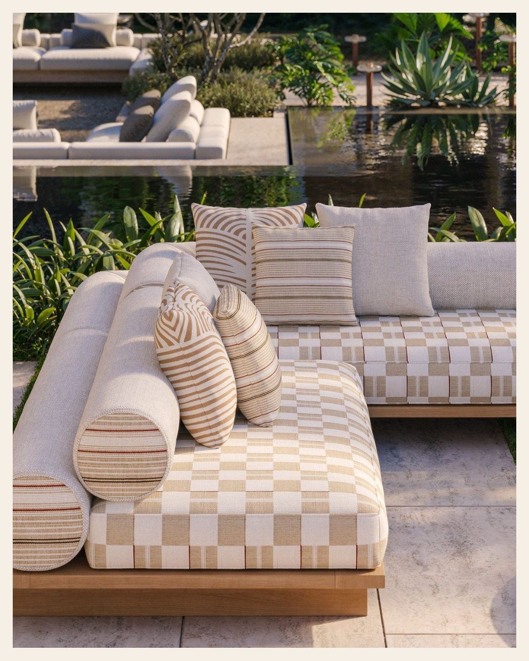 Neutral patterned outdoor lounge seating with striped pillows near a dark garden pool.