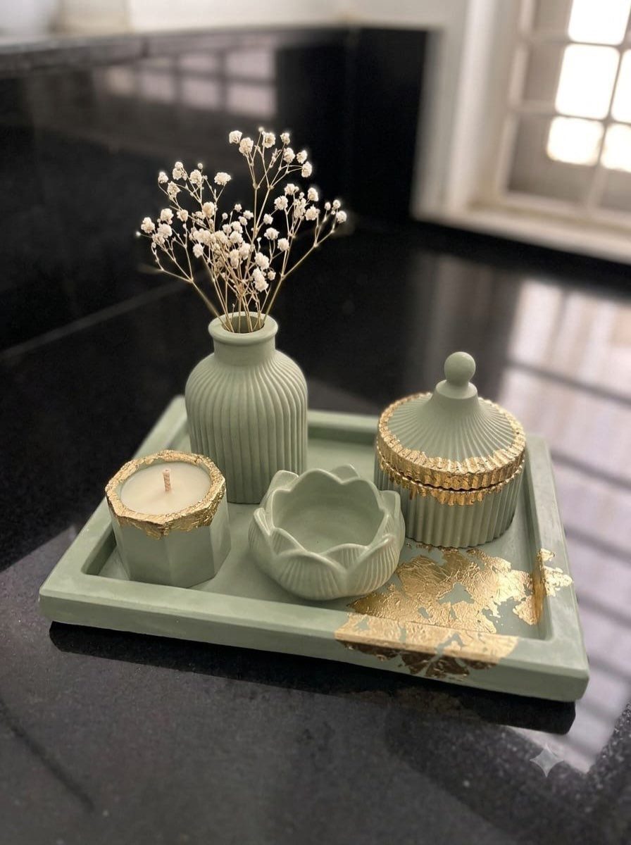 Sage green decorative tray holding a small vase, candle, lotus bowl, and lidded jar.