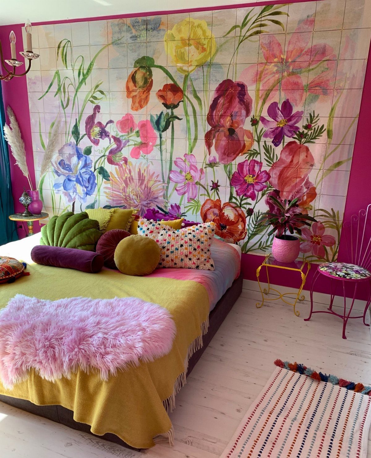 Colorful bedroom with a large floral mural, bright yellow bedding, and eclectic pink furniture.
