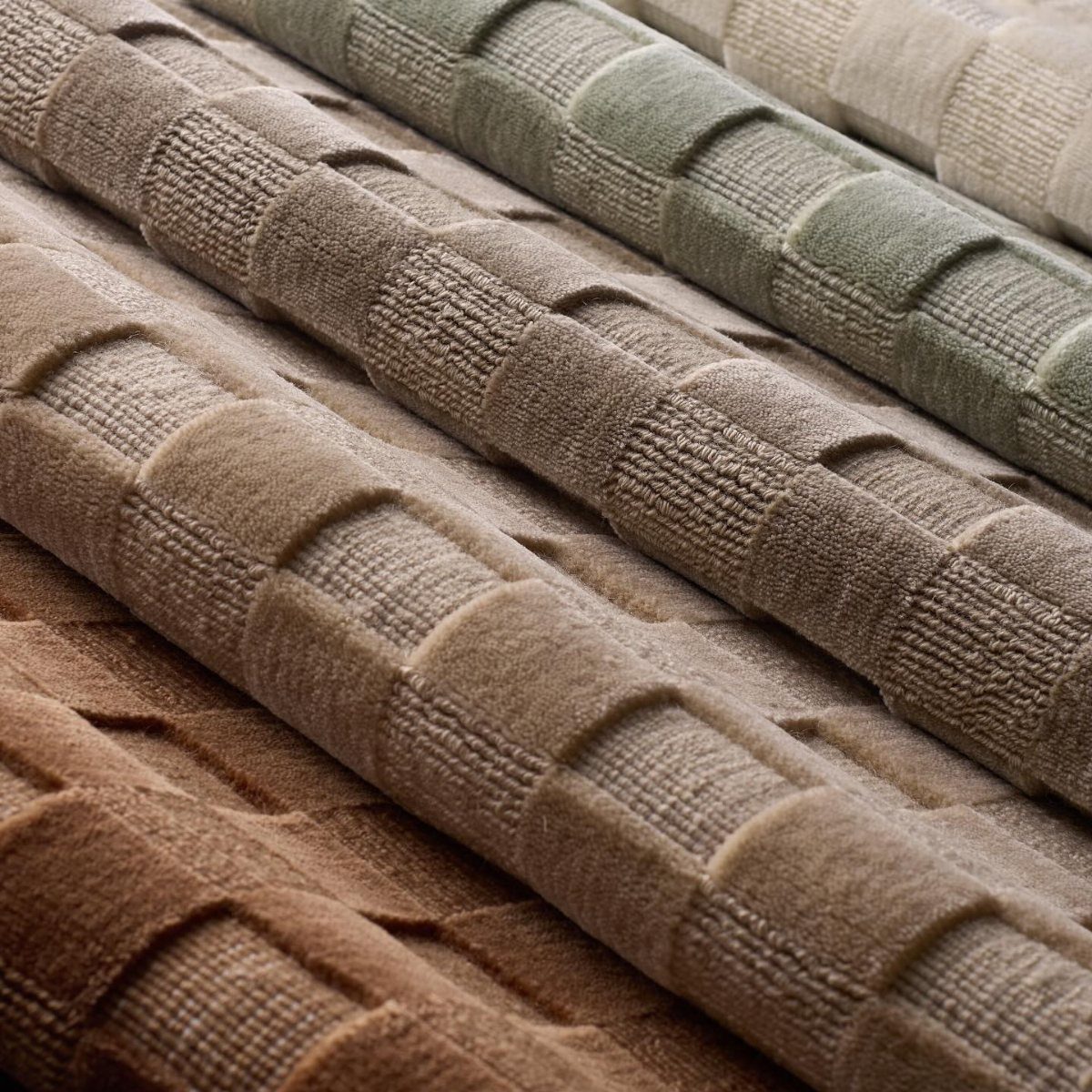 Rolled textured rugs in brown, tan, and sage green with a raised grid pattern.