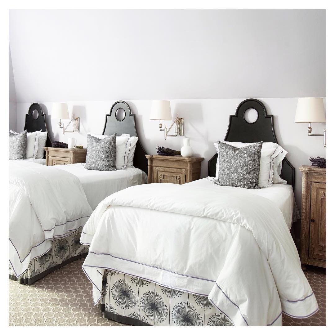 Two twin beds with white bedding and botanical patterned bedskirts in a bright bedroom.