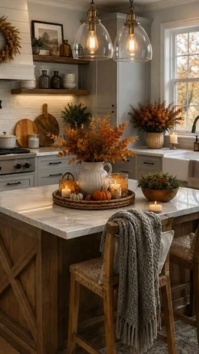 Wooden kitchen island decorated with autumn leaves, pumpkins, and glowing candles.
