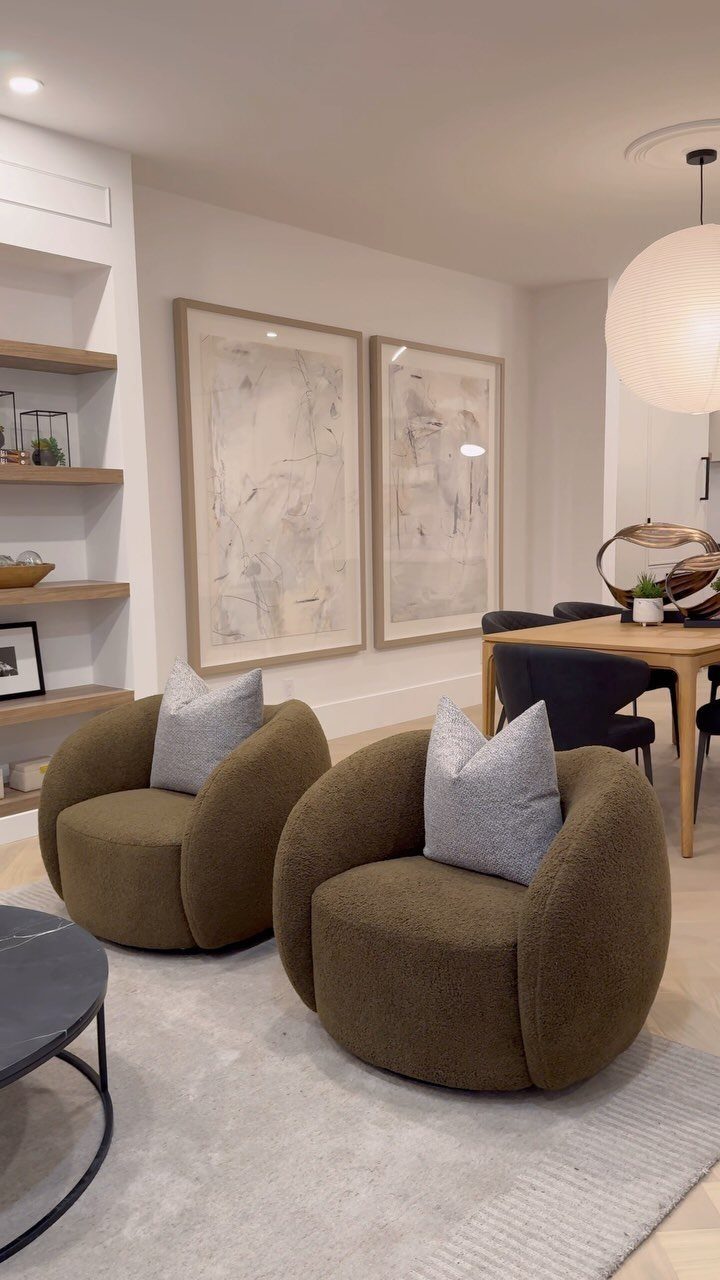 Two olive green swivel chairs with grey pillows arranged on a light rug.
