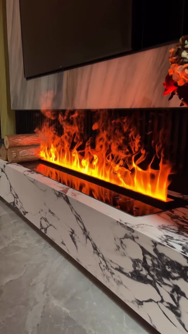 A modern linear electric fireplace with bright orange flames set into a white marble base.