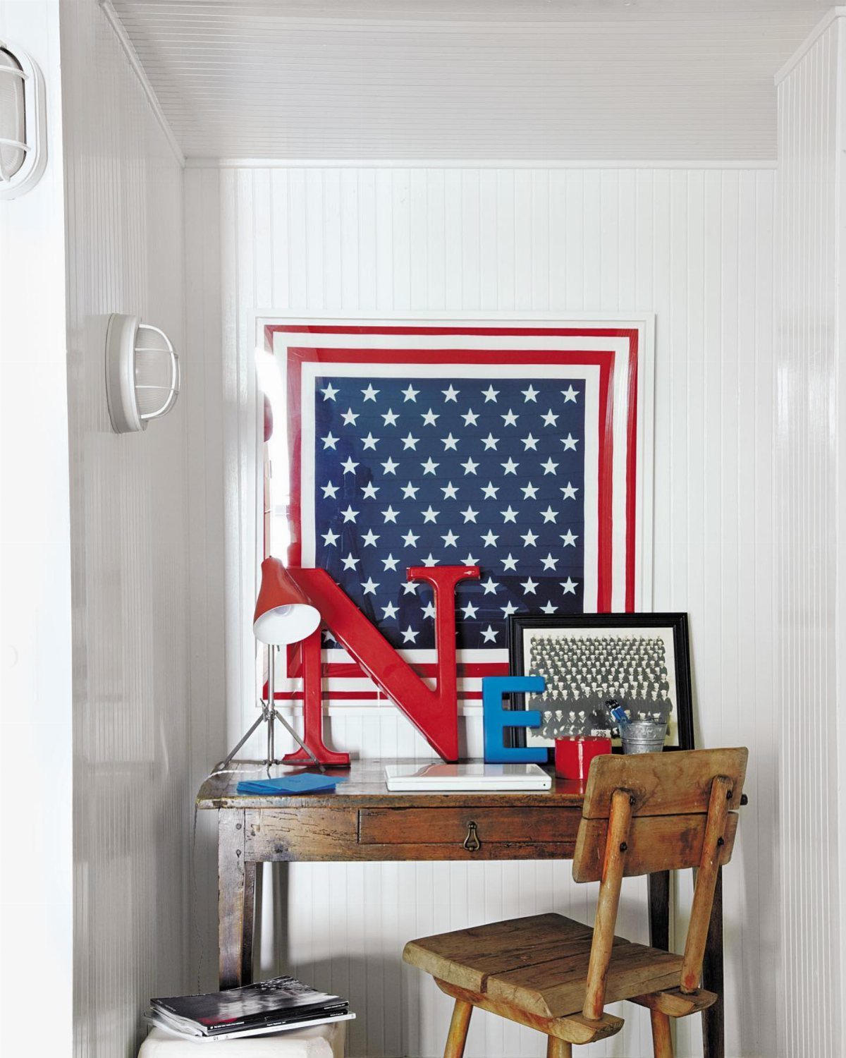 A wooden desk decorated with large red and blue letters and a framed picture in a white nook.