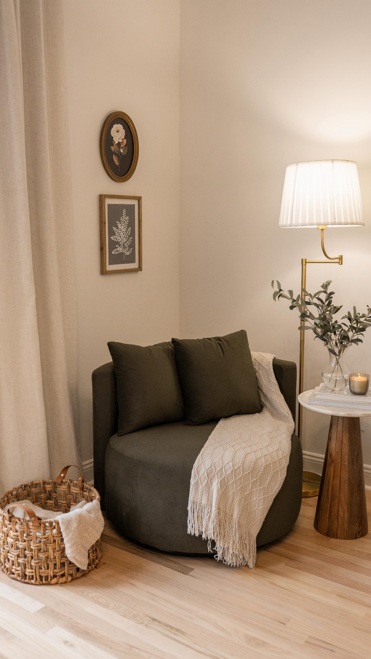 Dark green swivel chair with cream throw next to a marble side table and floor lamp.