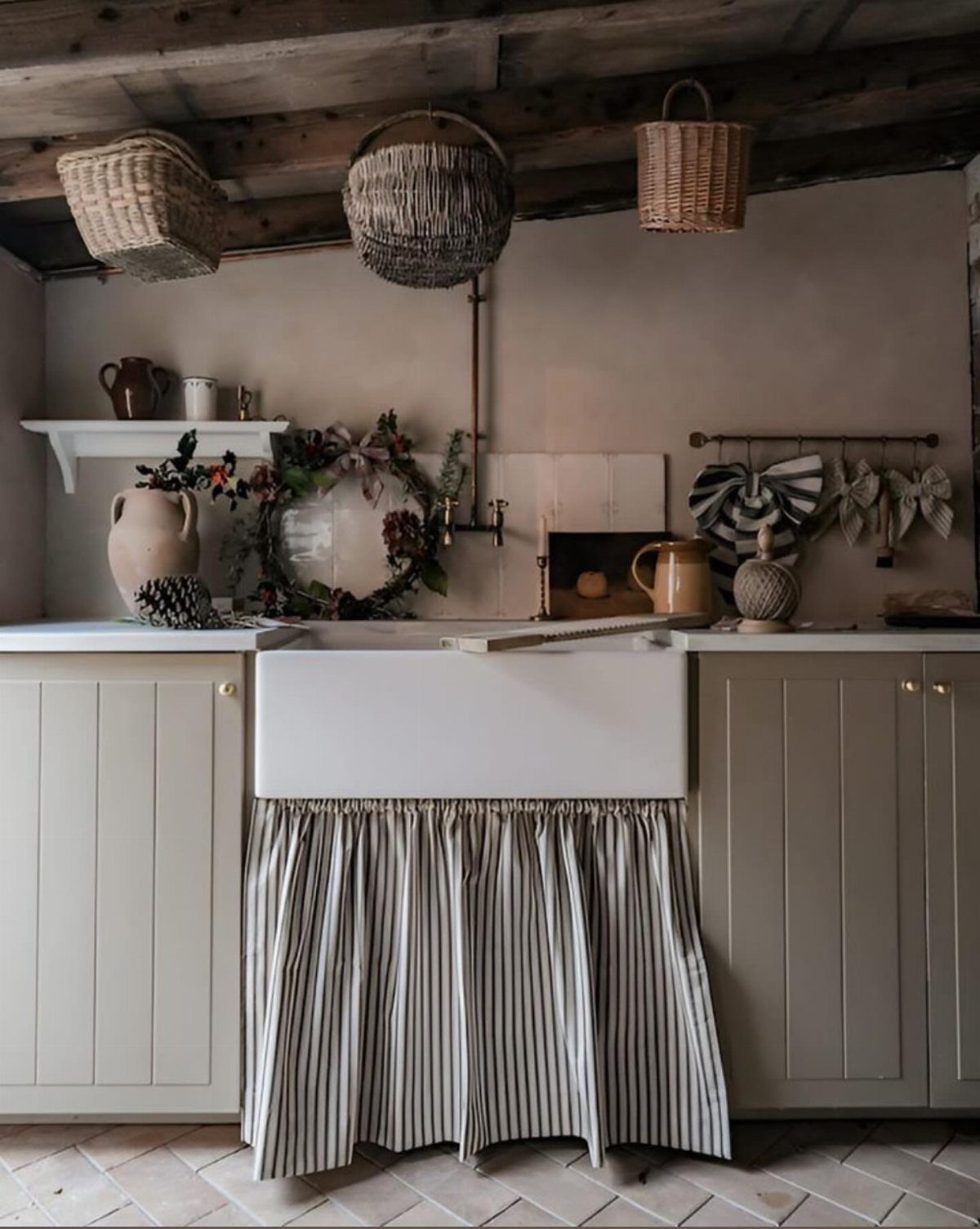 A white farmhouse sink featuring a black and white striped fabric skirt under a grey vanity.