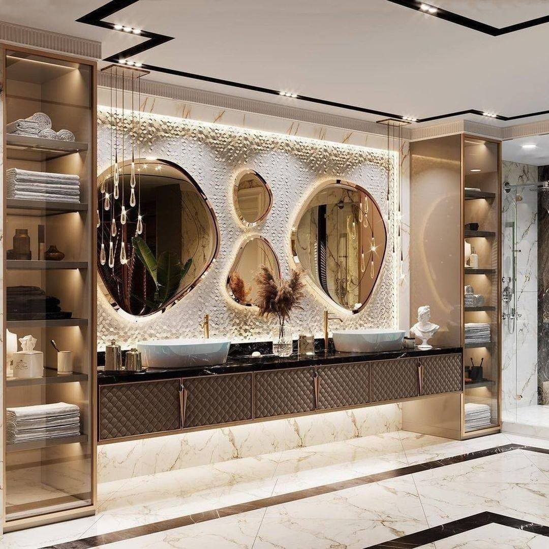 Three organic-shaped gold mirrors mounted on a textured white wall above a luxury bathroom vanity.