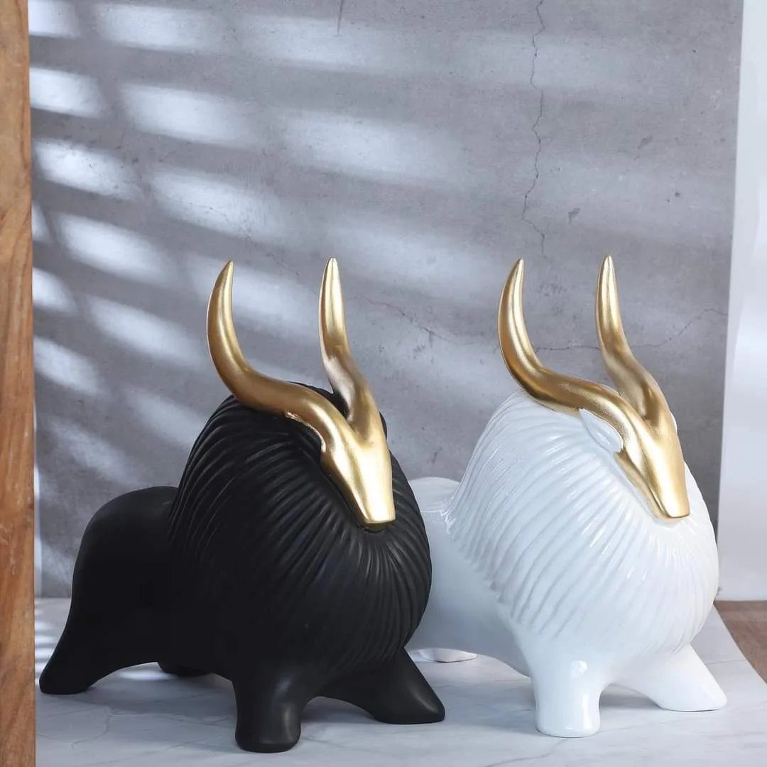 Black and white animal figurines with gold horns sitting on a marble surface.