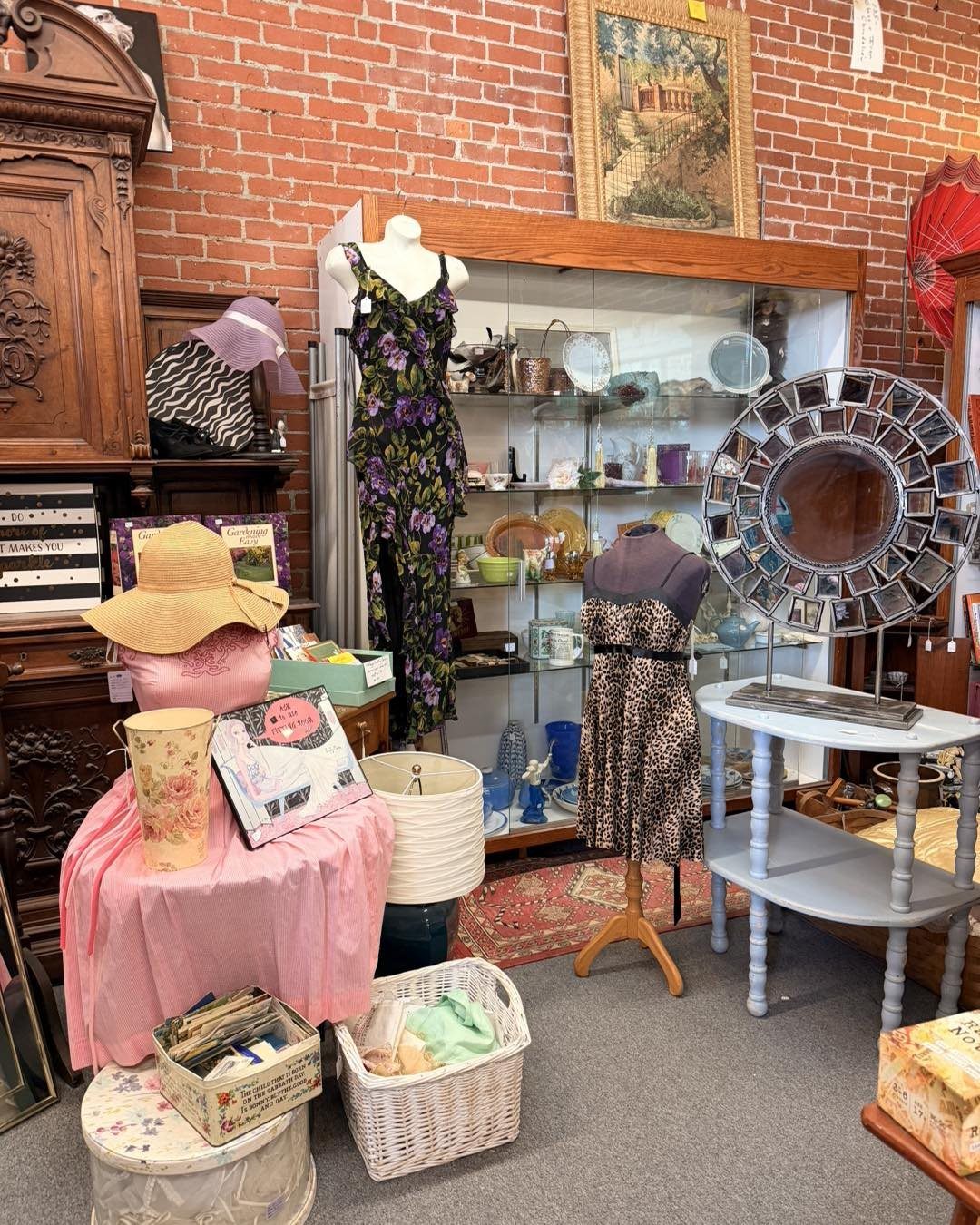Various secondhand items including dresses, hats, and glassware displayed inside a thrift store.