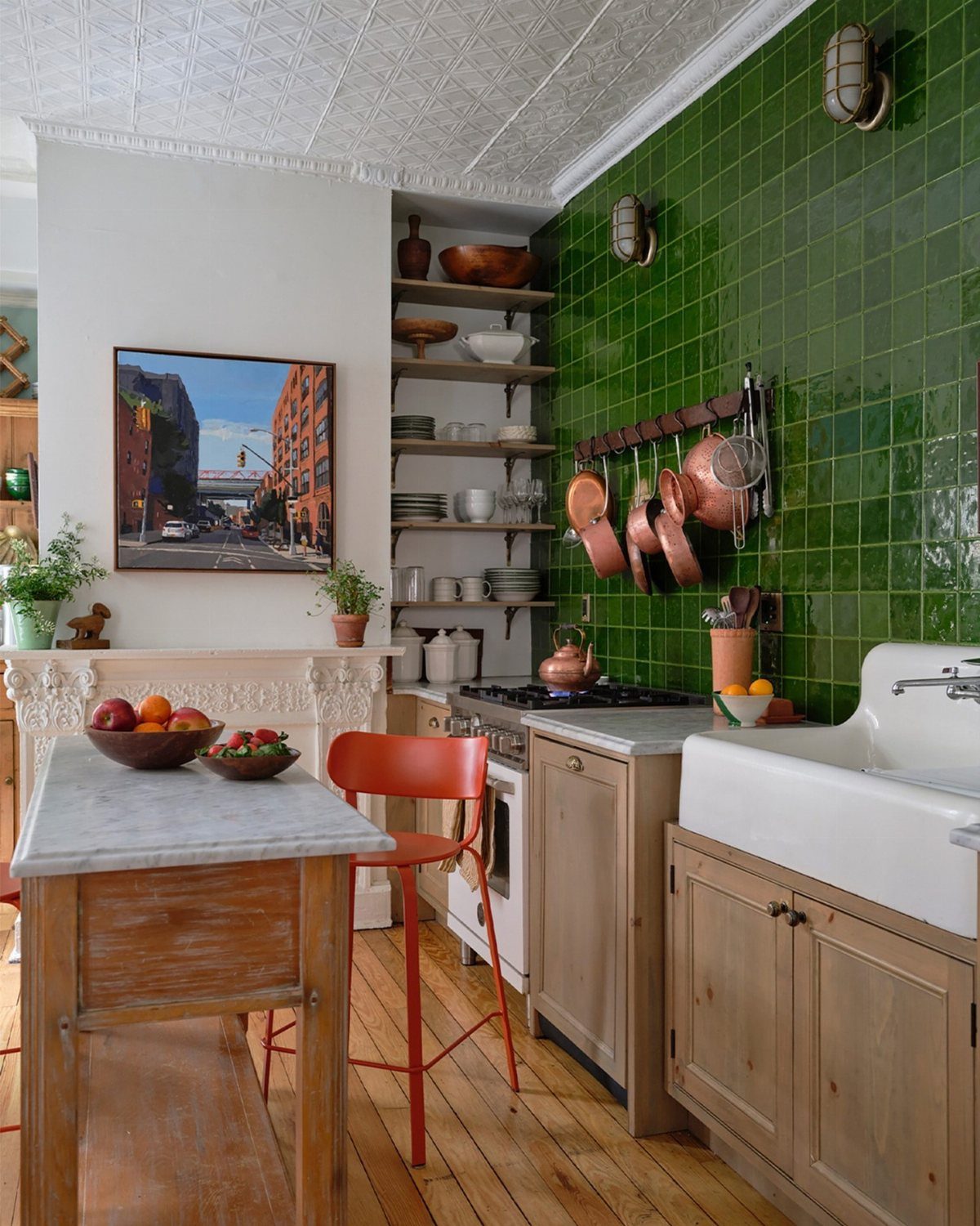Emerald green tiled walls in a kitchen with wooden cabinets and marble countertops.