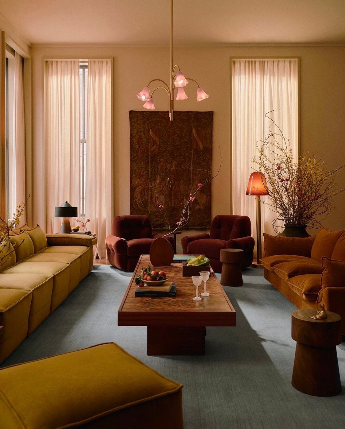 A warm living room with velvet seating, a wooden coffee table, and a large wall tapestry.