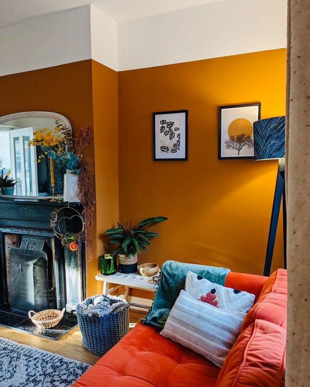 Orange sofa and walls in a living room with a fireplace and plants.
