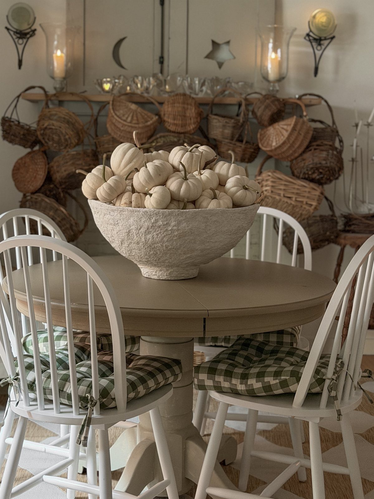 A large white bowl filled with small white pumpkins on a wooden dining table.