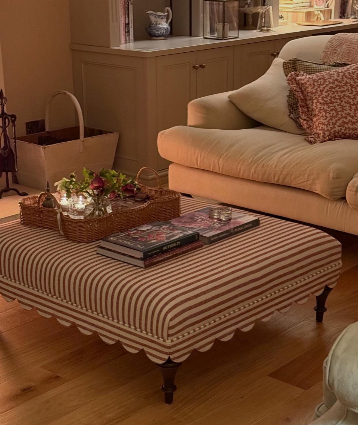 Striped upholstered ottoman used as a coffee table with a tray and books.