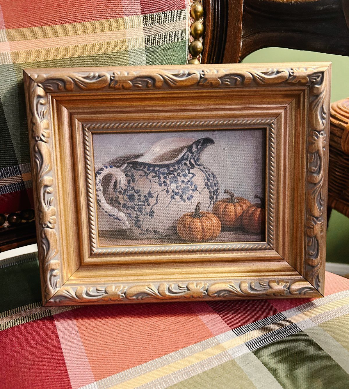 Ornate gold wooden frame featuring a still life print of a pitcher and pumpkins.