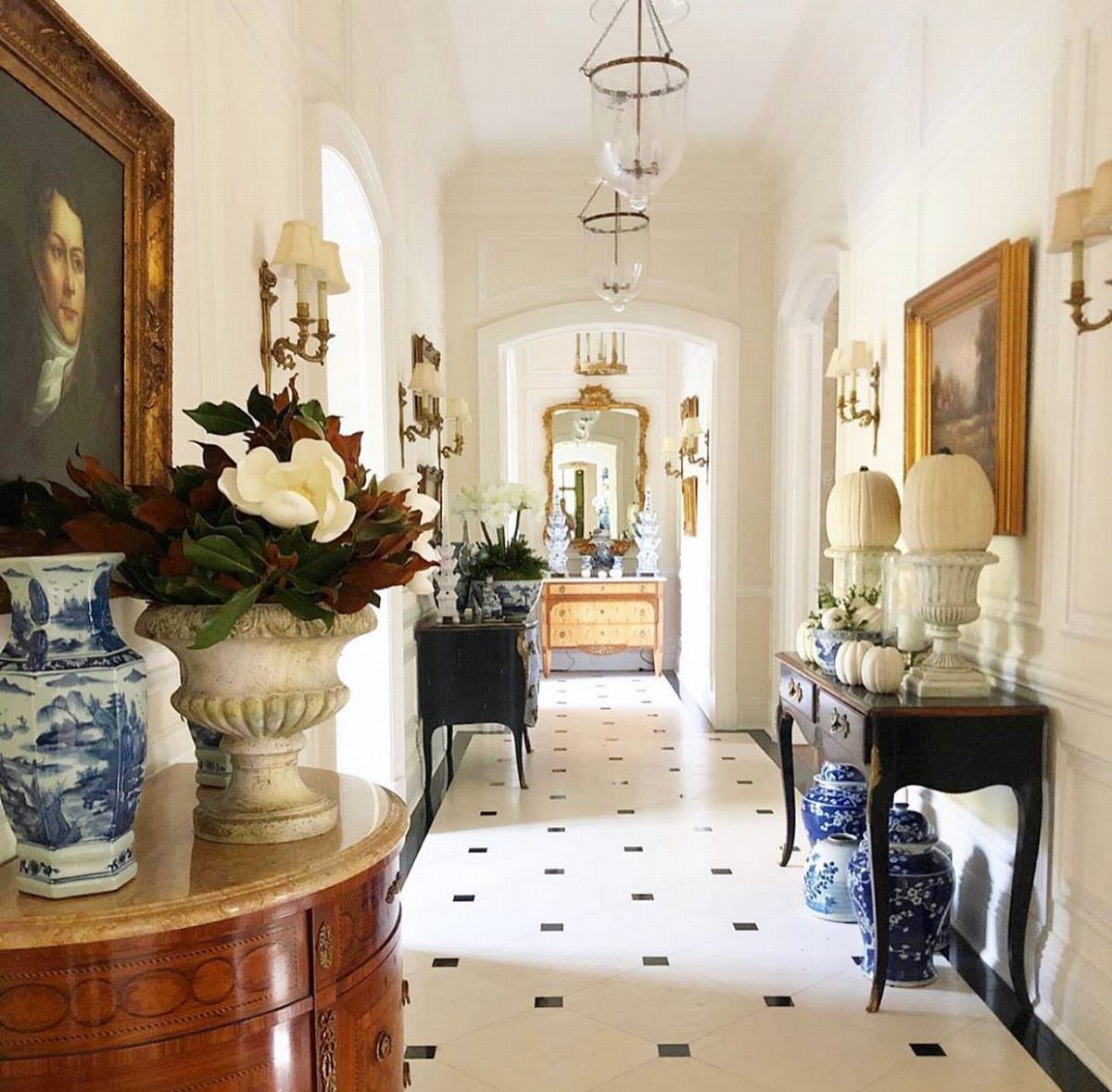 Blue and white chinoiserie ceramic jars and vases arranged on elegant hallway console tables.