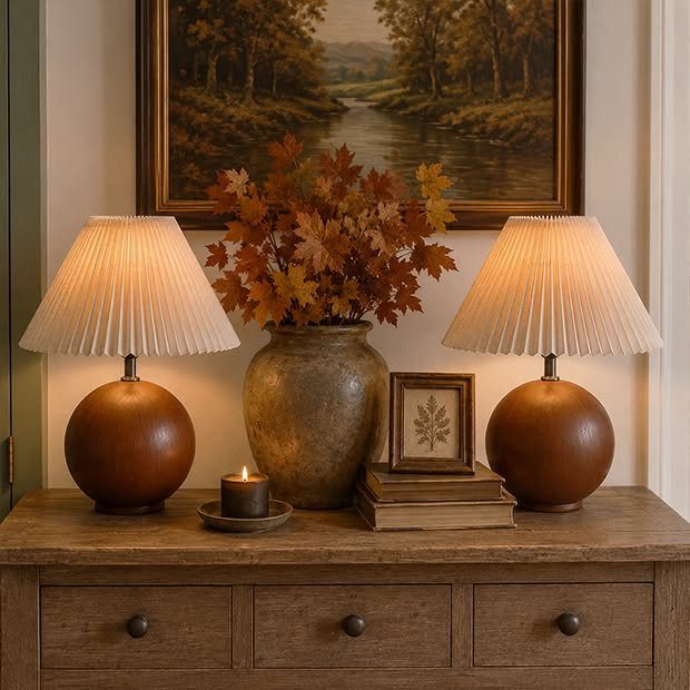 Two cordless table lamps with pleated shades and wooden bases on a wooden sideboard.