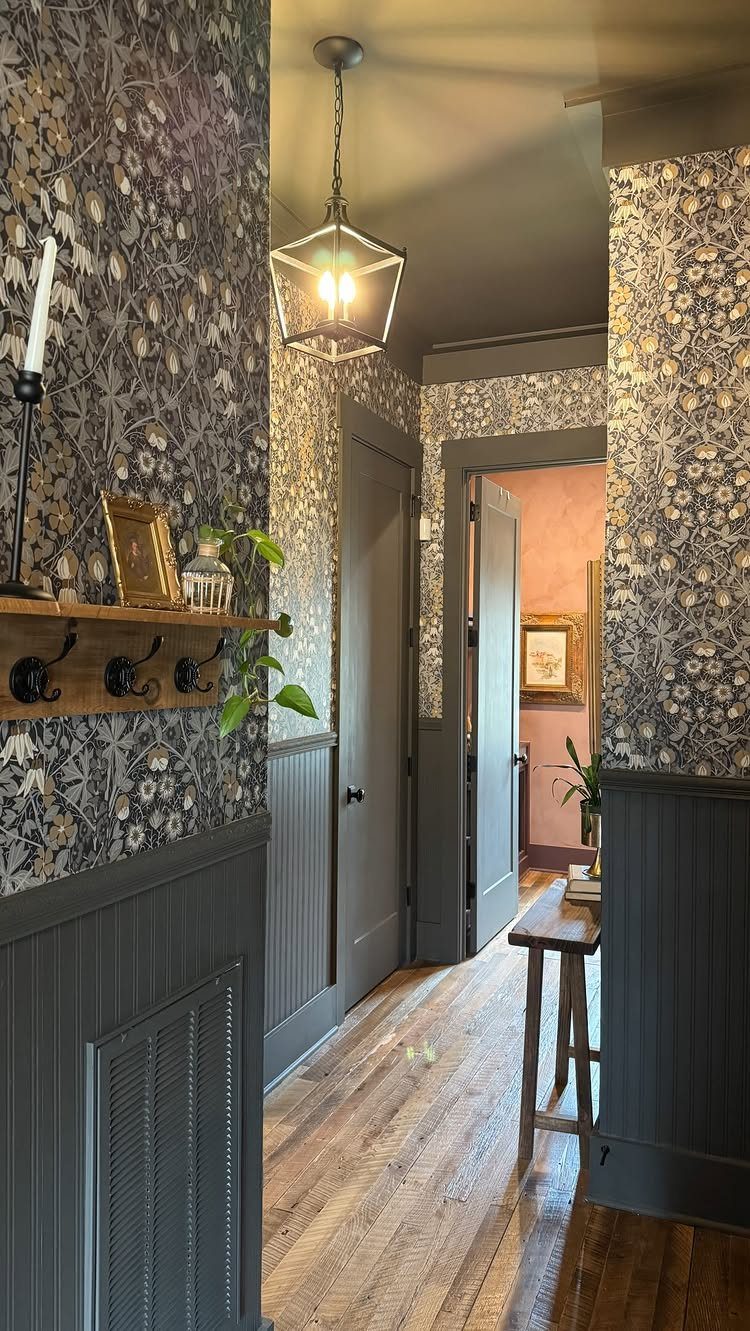 Dark floral wallpaper covers the upper walls of a narrow hallway with grey wainscoting.