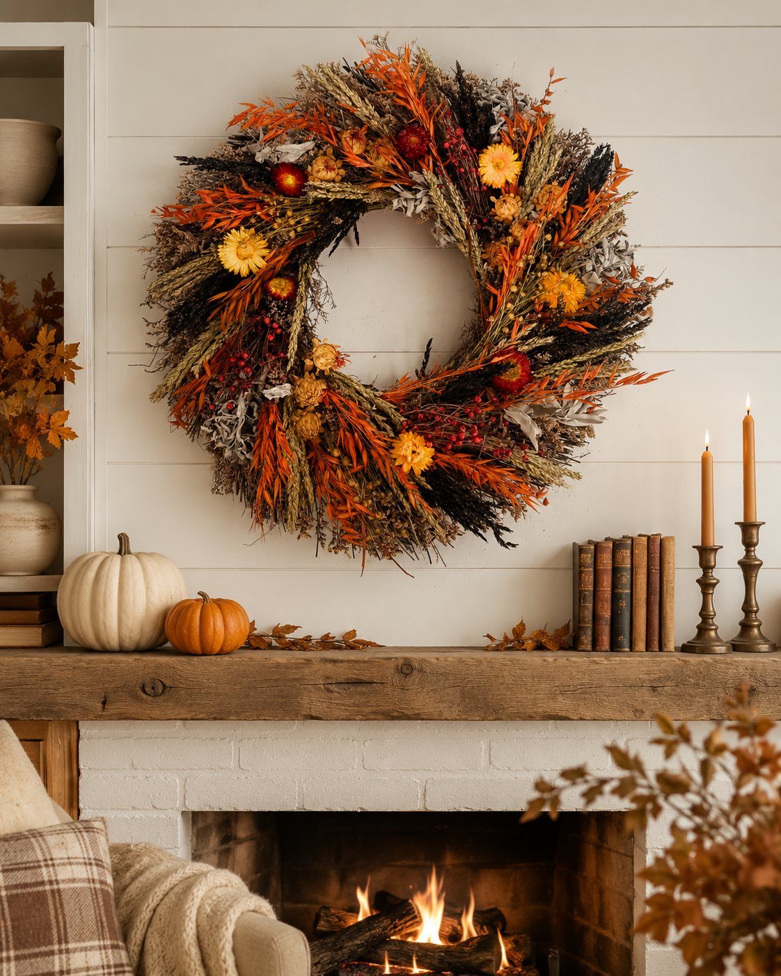 A large autumn wreath composed of dried grasses and colorful foliage hangs above a fireplace mantel.