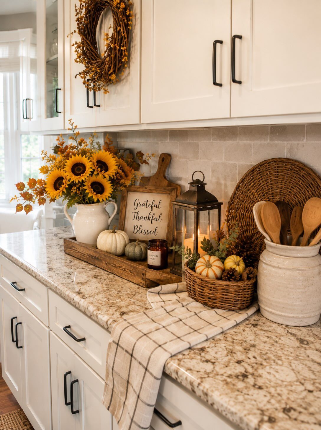Autumnal farmhouse decor featuring sunflowers, pumpkins, and a lantern on a granite kitchen countertop.