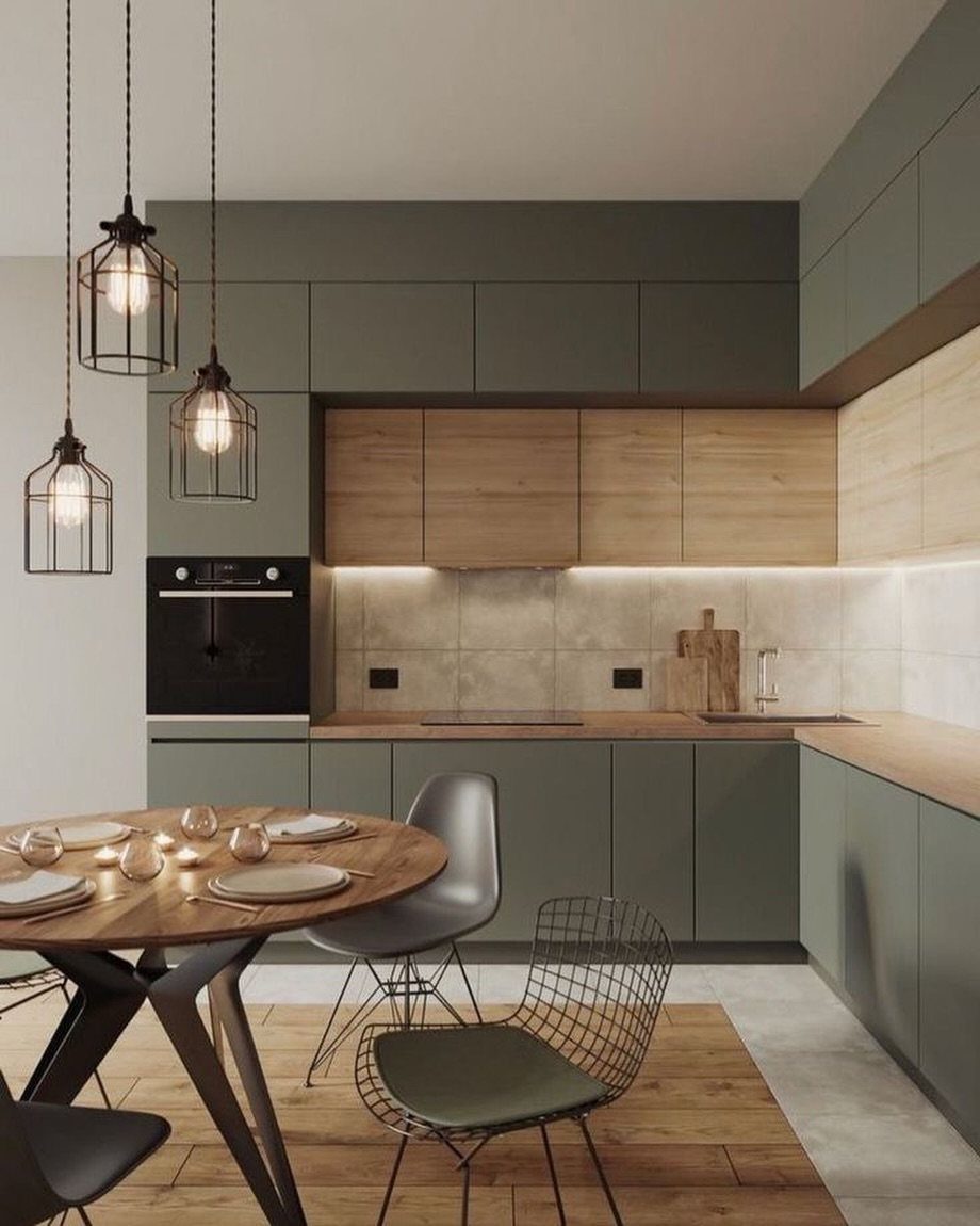 Modern kitchen with green cabinets, wooden countertops, and a round wooden dining table.