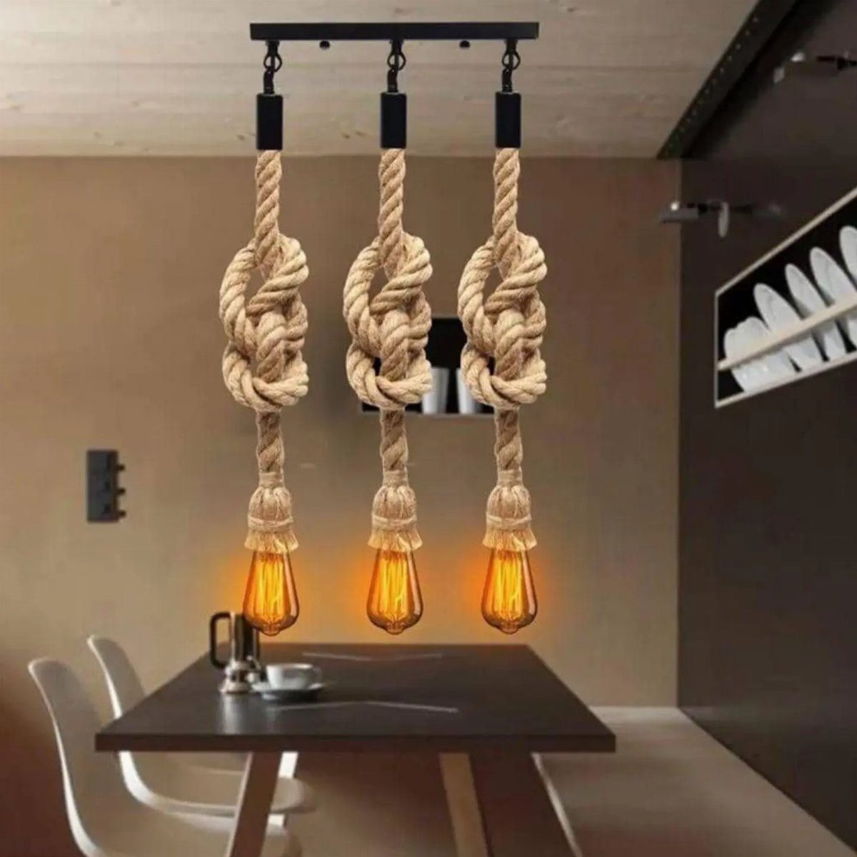 Three rope pendant lights with glowing Edison bulbs hanging over a dark dining table.