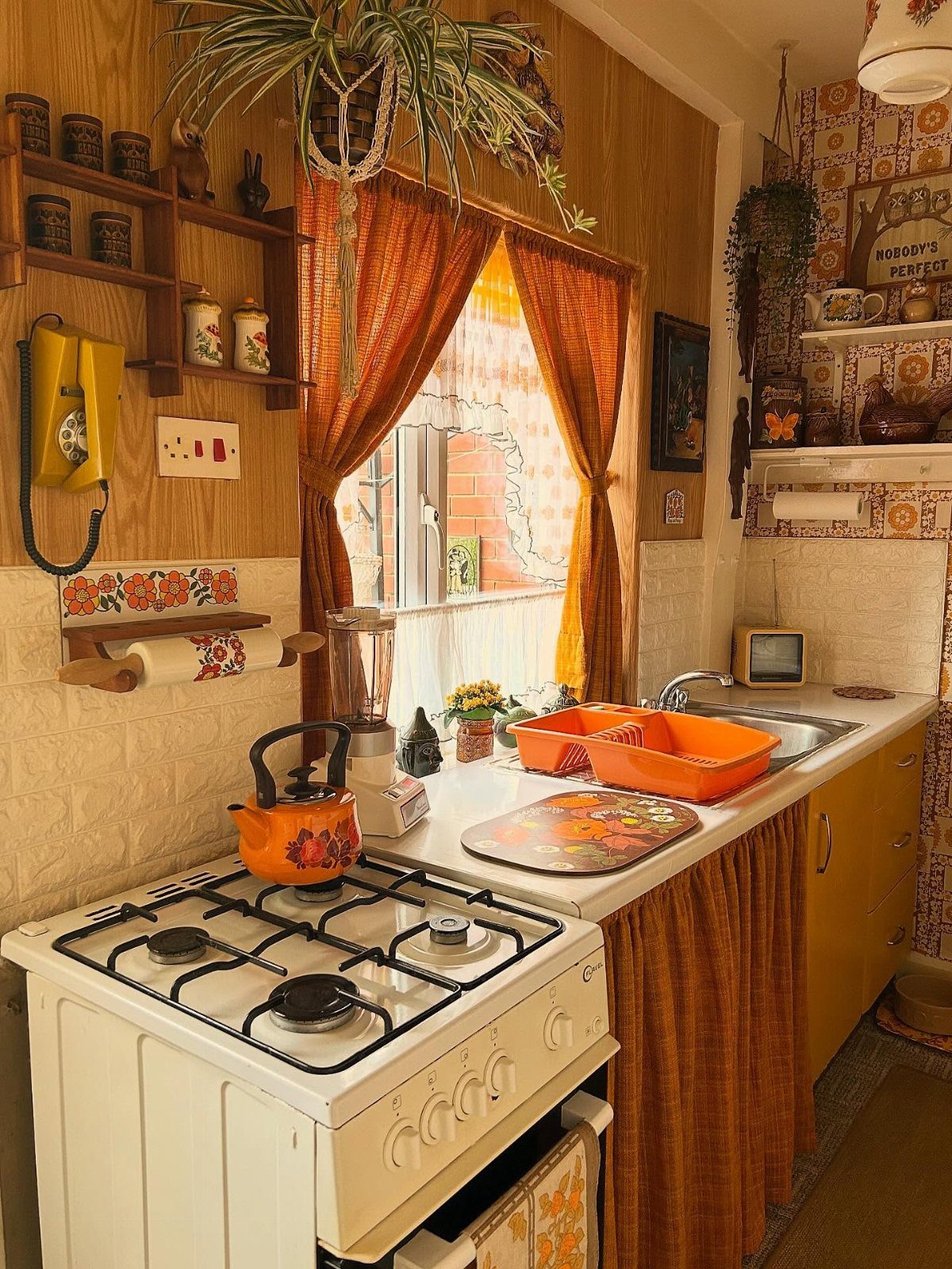 A cozy, eclectic kitchen with orange curtains, a white stove, and vintage decor items.