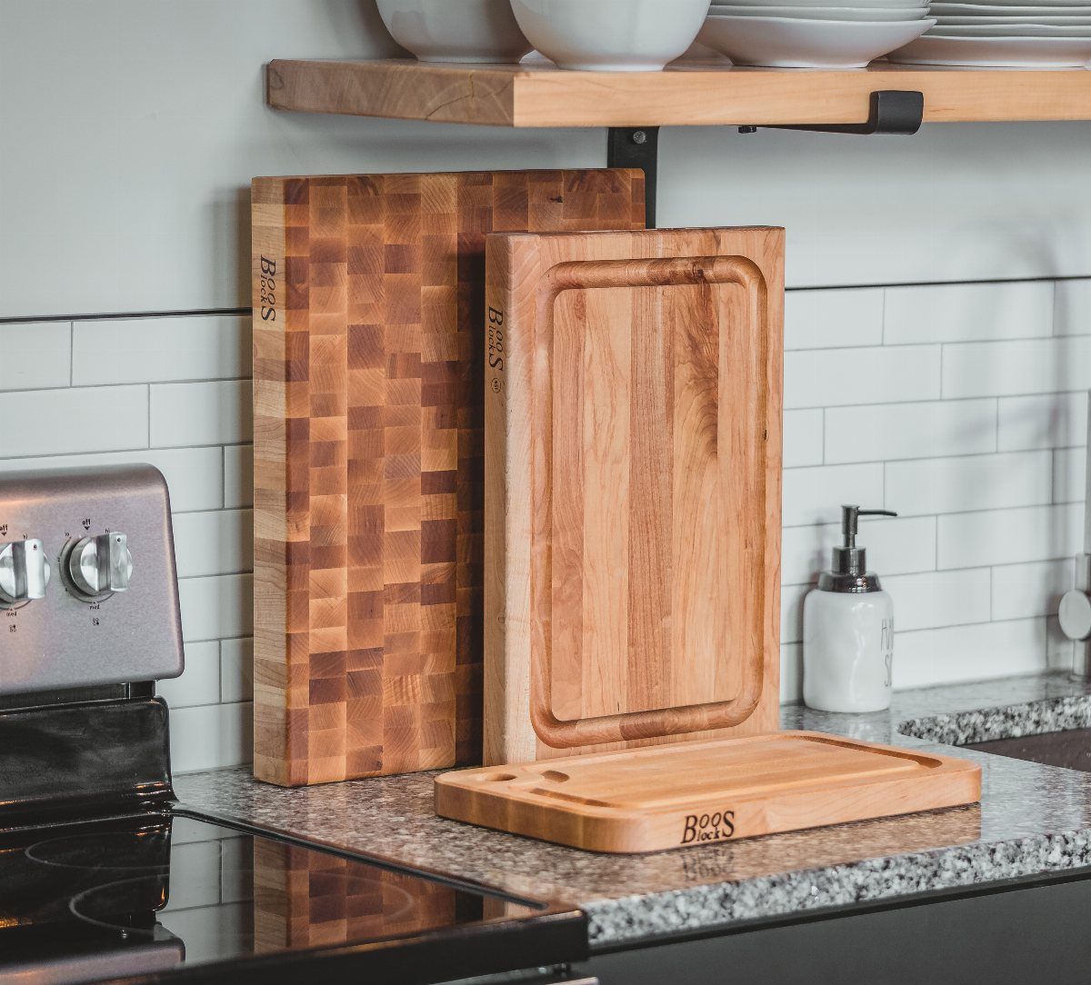 Three wooden cutting boards of different styles arranged on a granite kitchen countertop.