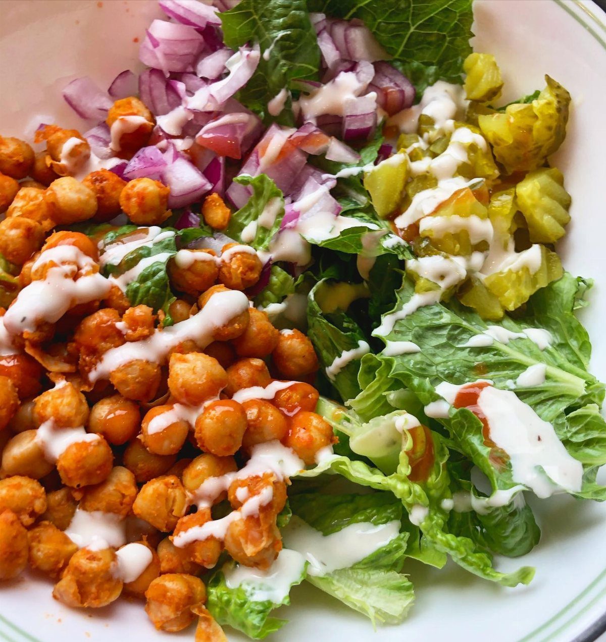 Roasted buffalo chickpeas served on a salad with lettuce, red onion, and pickles.