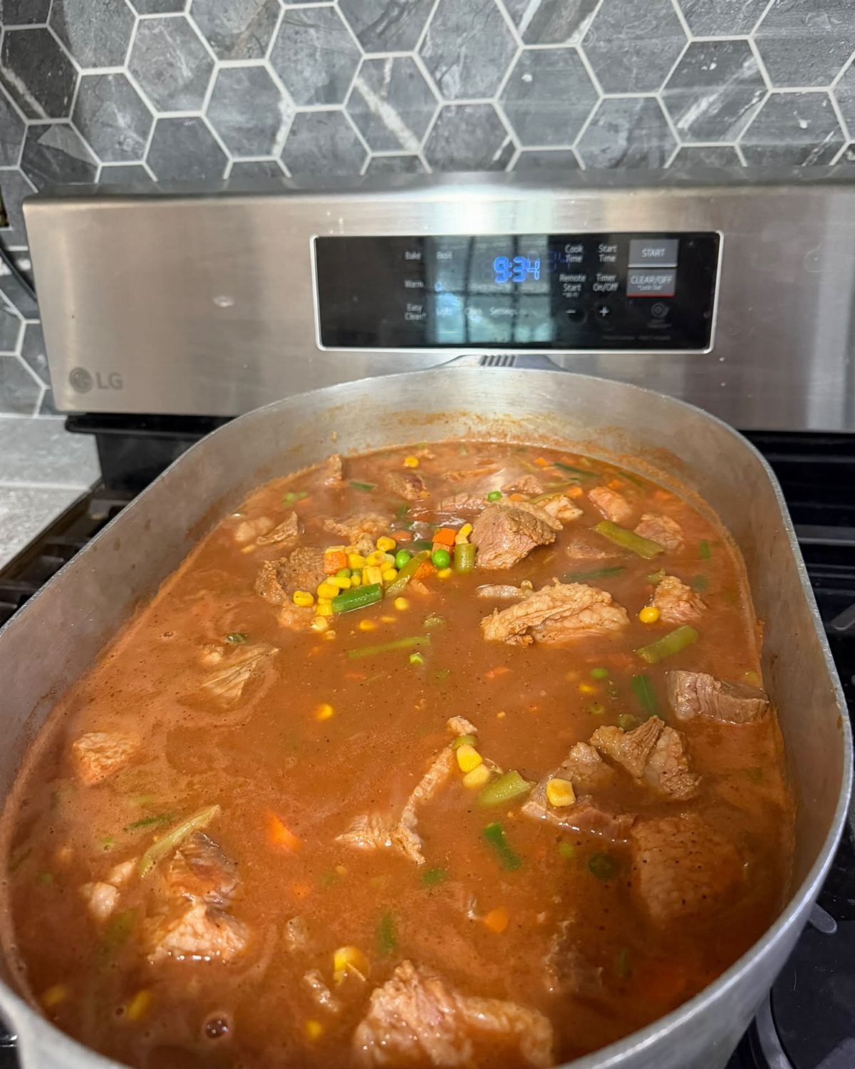 A large silver pot filled with meat and vegetable stew on a stove.