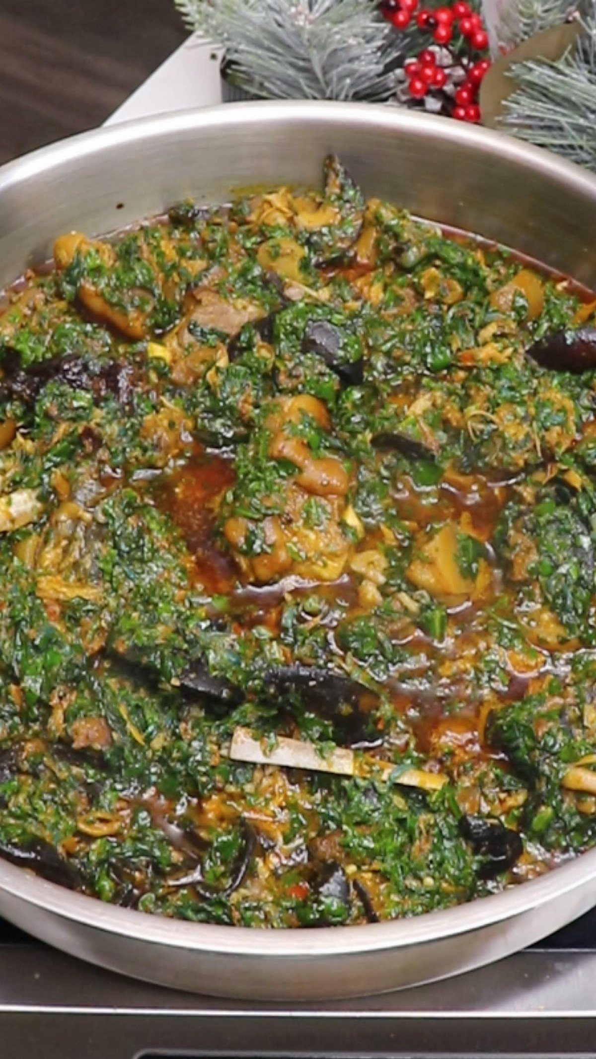 A large silver pan filled with a thick, dark green leafy vegetable stew.