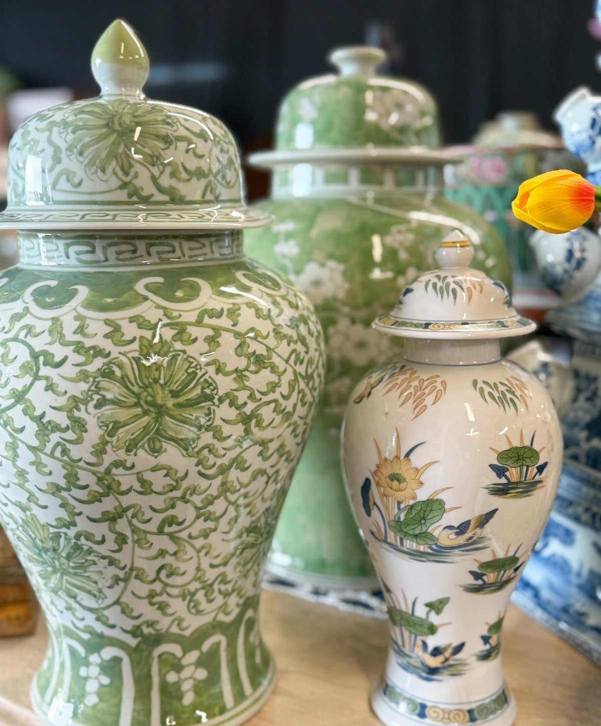 Green and white patterned ceramic ginger jars arranged together on a wooden surface.