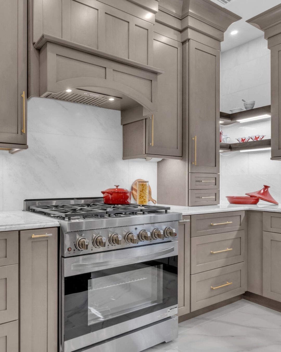 Taupe kitchen cabinets with decorative crown molding above a stainless steel gas range.