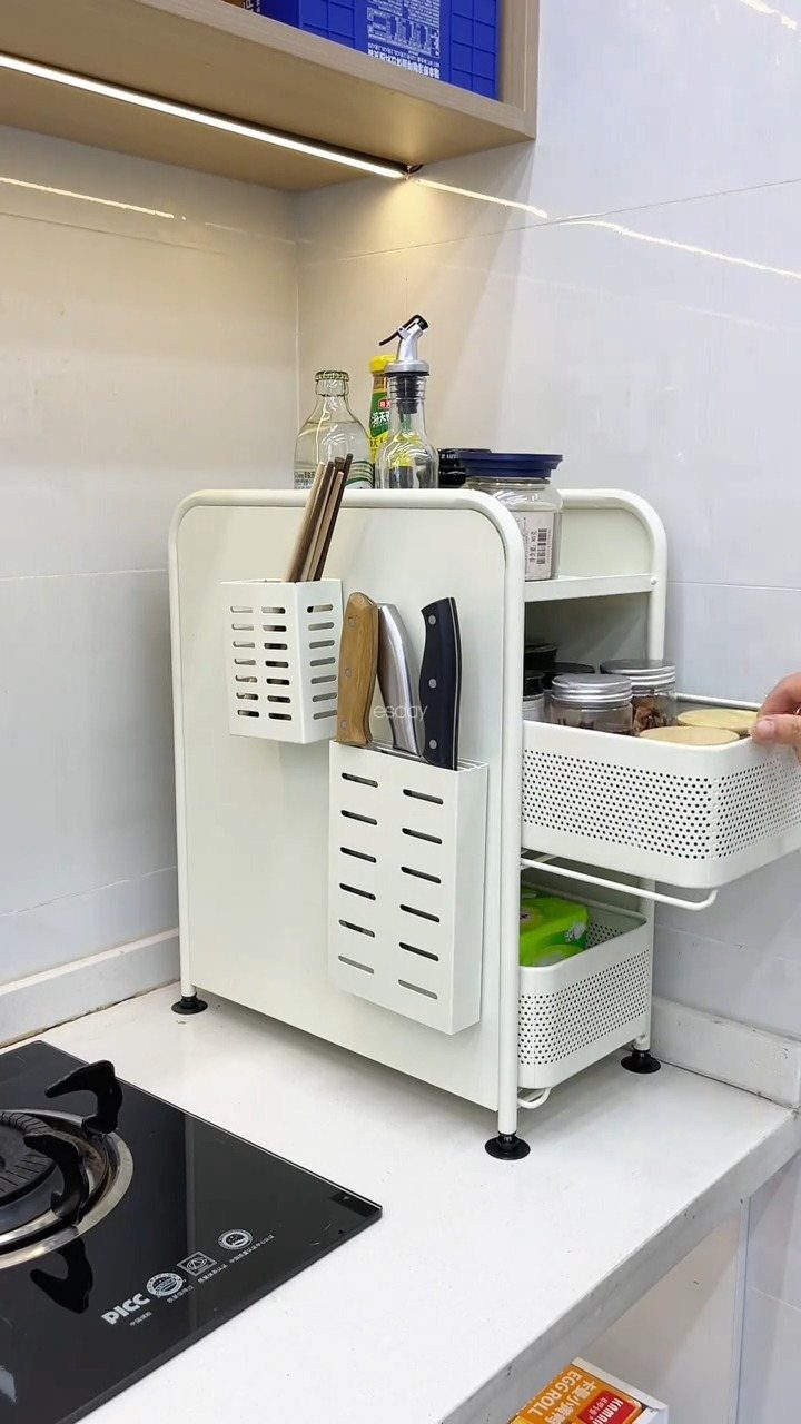 White metal kitchen organizer with knife slots and two pull-out sliding mesh drawers on a countertop.