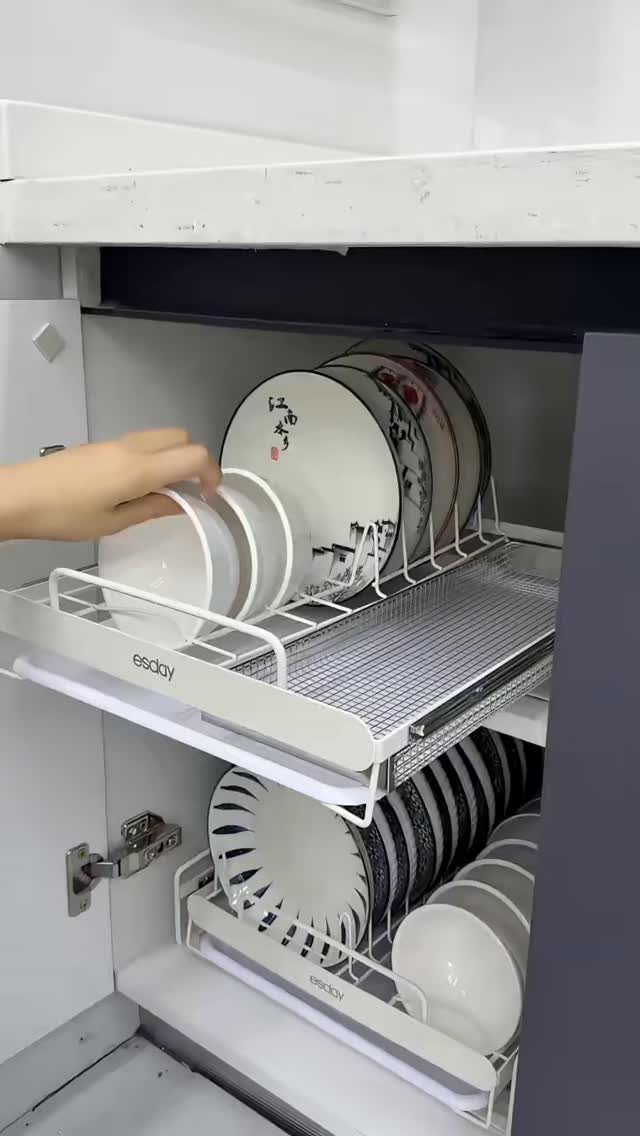 A hand reaching for a white bowl on a sliding metal tray inside a cabinet.