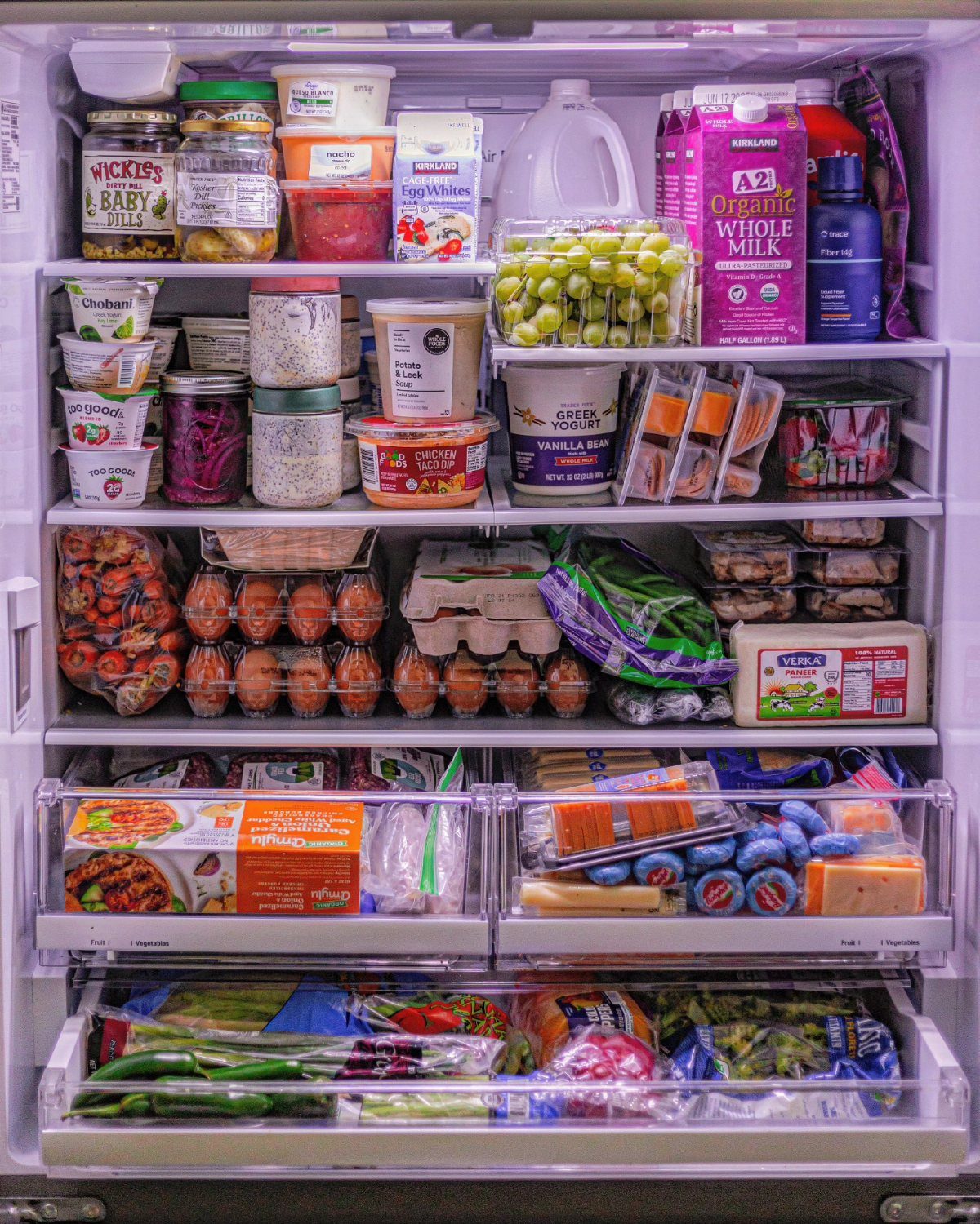 A fully stocked refrigerator with organized shelves containing eggs, dairy, and various packaged food items.