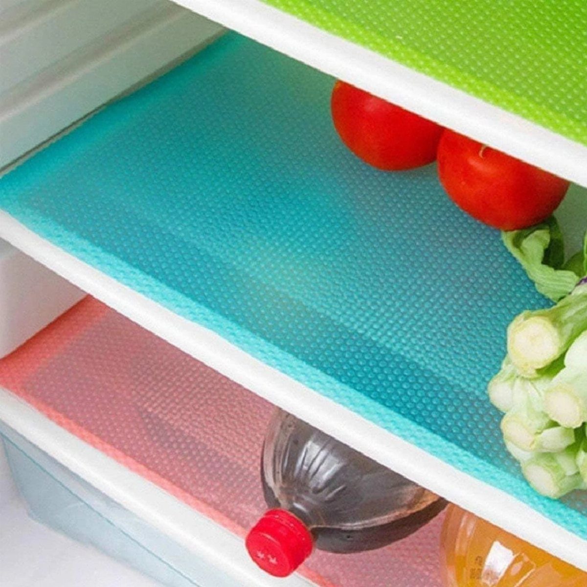 Teal and red textured plastic mats lining the shelves of a refrigerator containing vegetables and bottles.