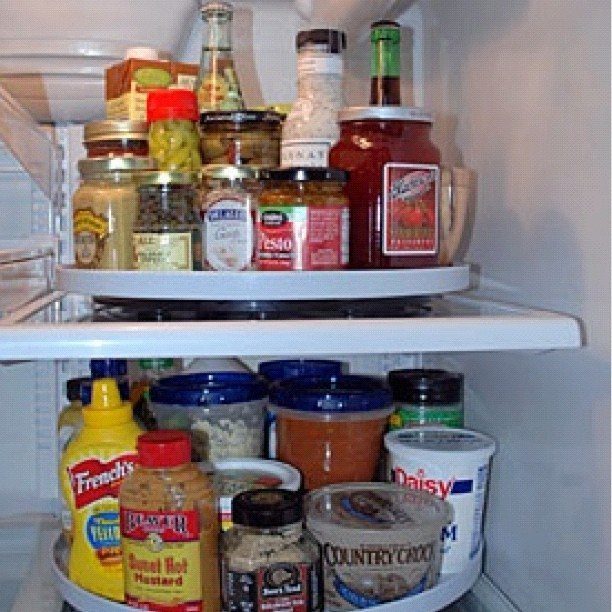 White plastic turntables holding various jars and condiment containers inside a refrigerator shelf.