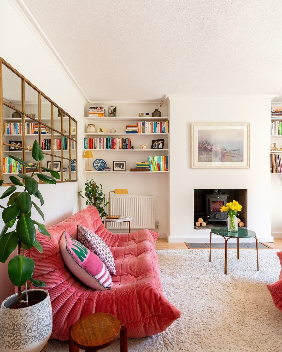 A bright living room featuring a bold pink velvet sofa and white textured rug.