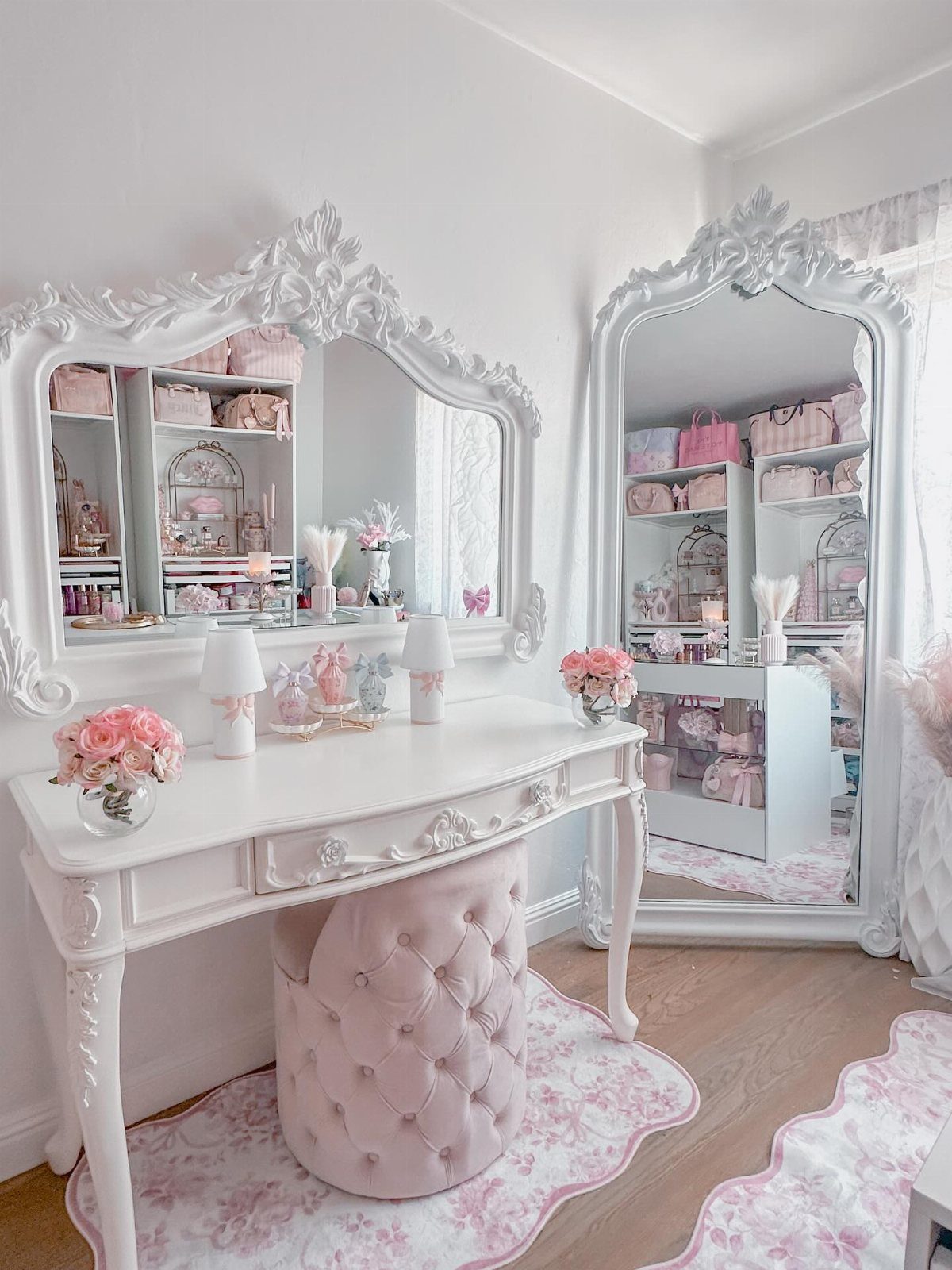 Ornate white vanity desk with a carved mirror and pink tufted velvet stool.