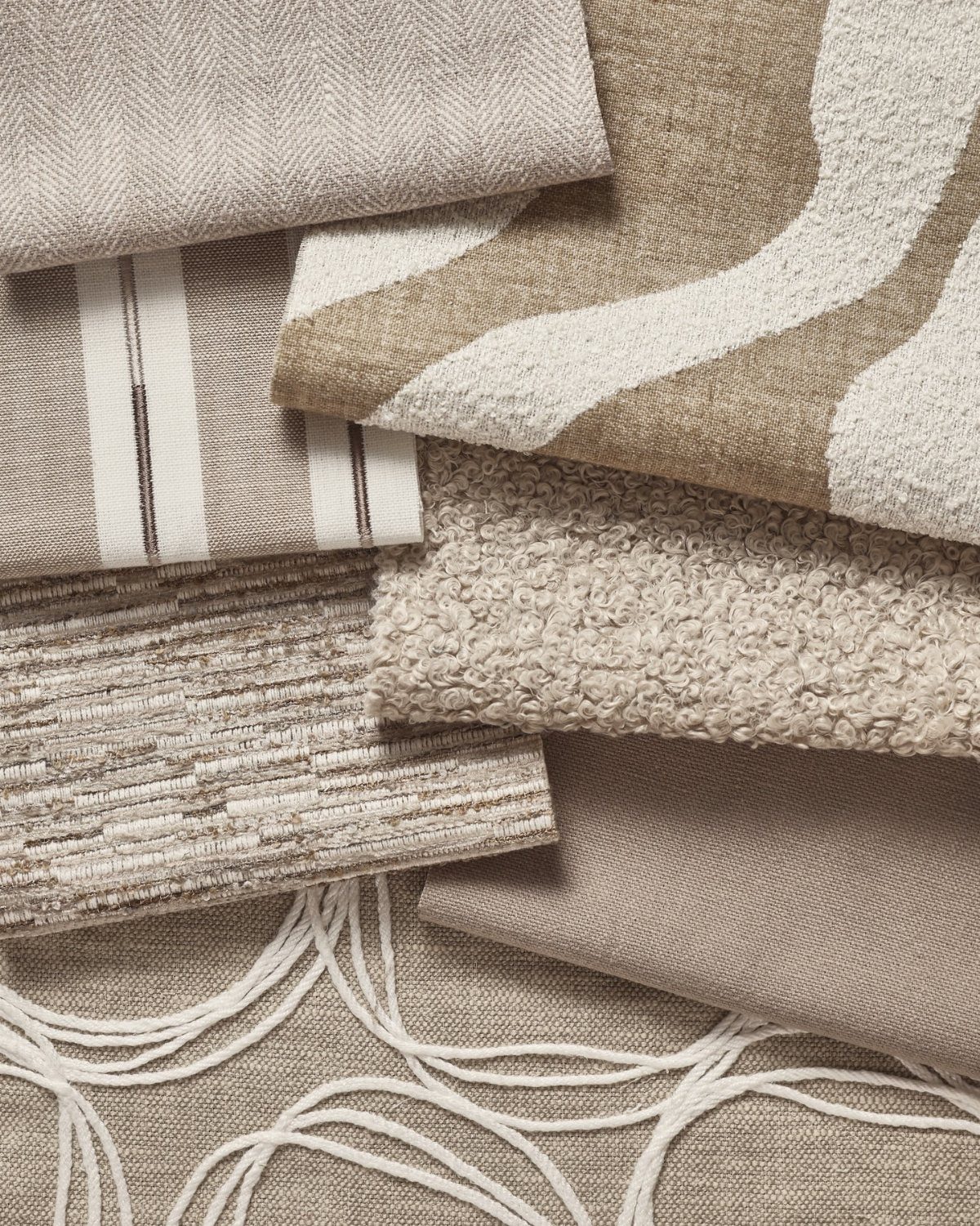 Layered fabric swatches in neutral beige and cream tones showing various woven textures.