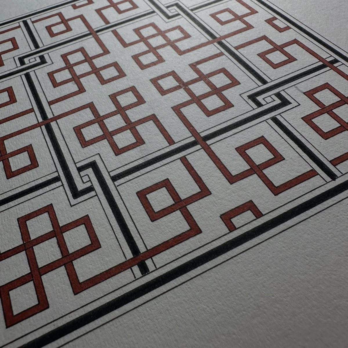 Interlocking red and black geometric lines forming a repeating pattern on white textured paper.