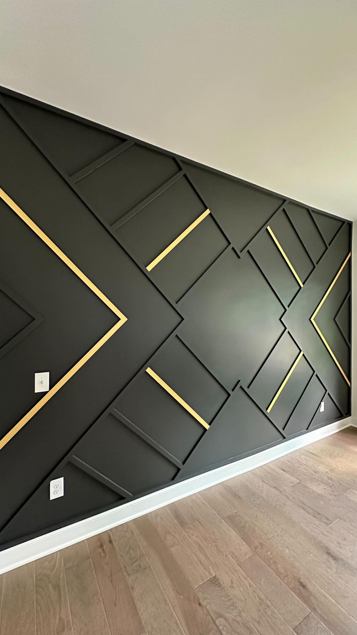 Black geometric accent wall with gold inlay lines and raised 3D patterns.