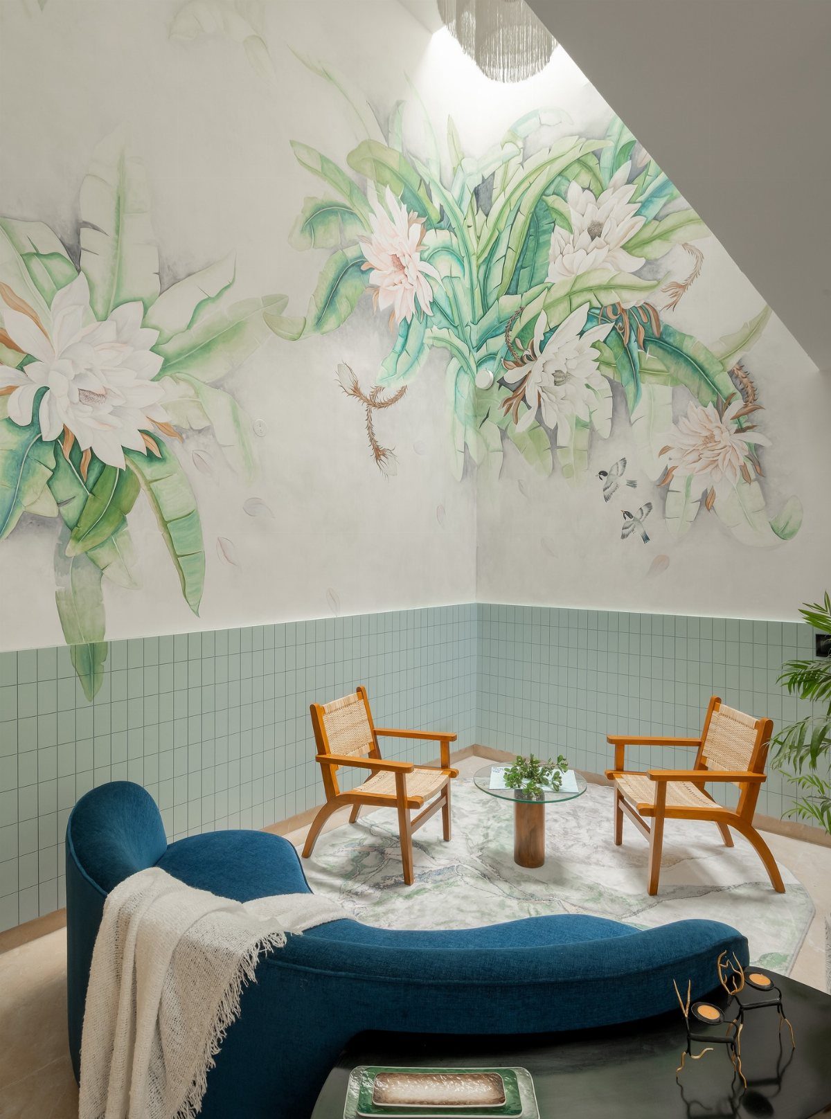 Living room with a large white lily mural, blue sofa, and two wooden armchairs.
