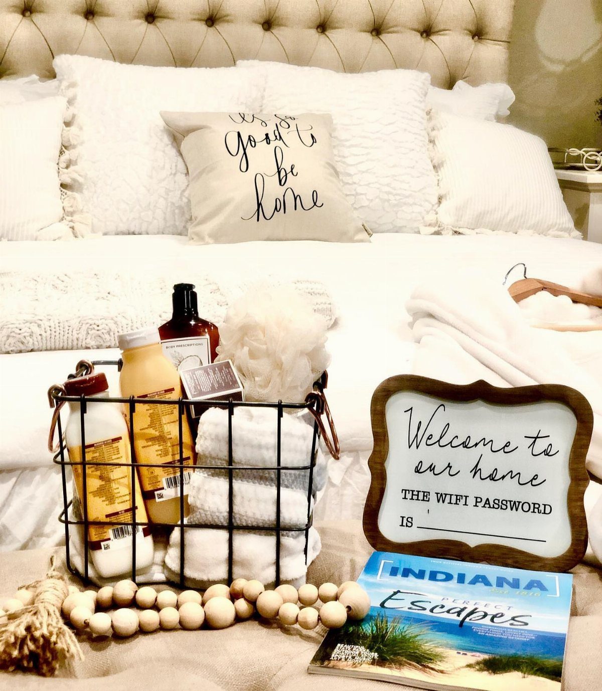 A black wire basket filled with rolled white towels and toiletries sits on a bed.